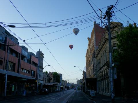 View south down Smith Street early morning, two hot air baloons drift by.