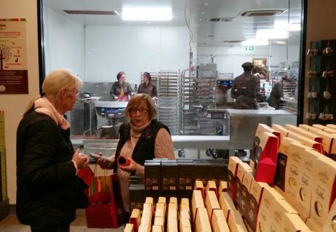 Two rather distinguished ladies discuss their purchases in a chocolate factory gift shop.